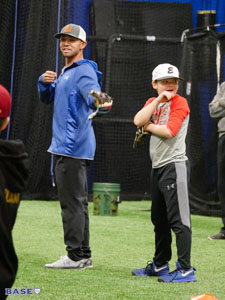 Coach Kai demonstrates a baseball drill with a volunteer.