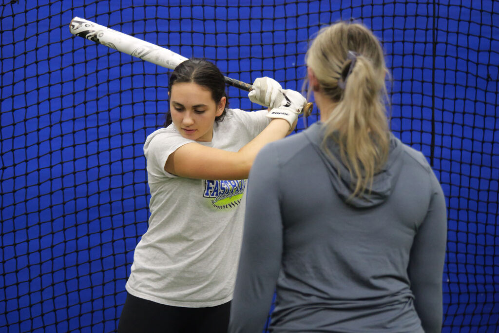 Softball Player Hits Off Tee While Coach Observes